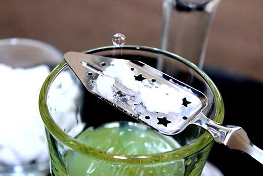 Absinthe drink in a glass with slotted absinthe spoon and sugar